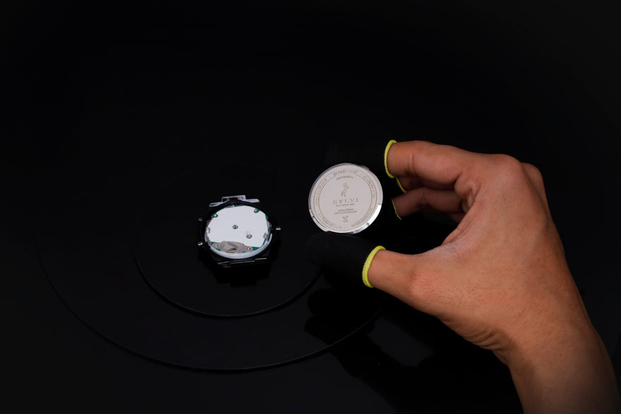 Hand holding a small metallic object on a dark background