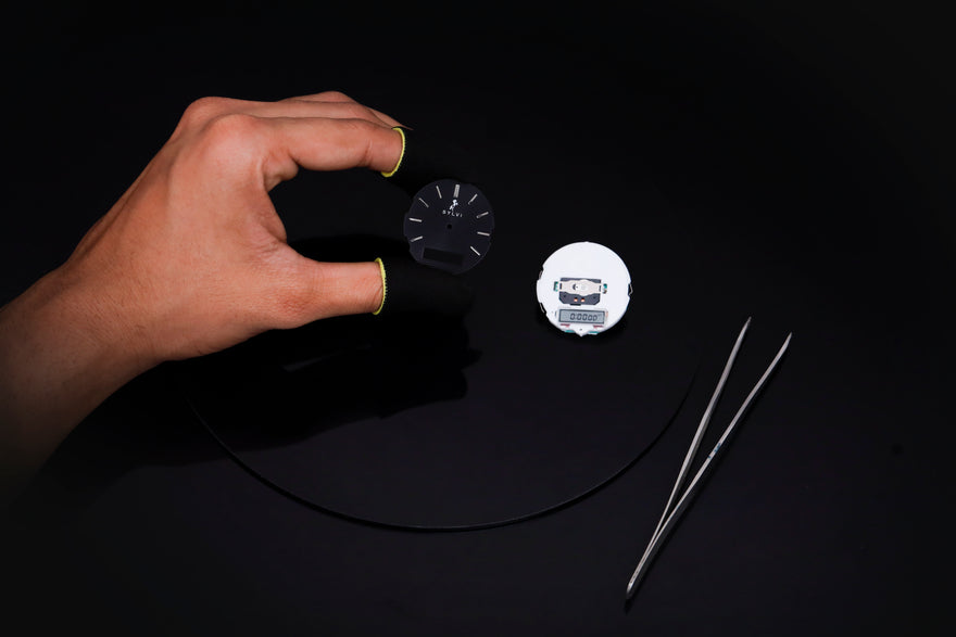 Hand holding a small round object with a black background
