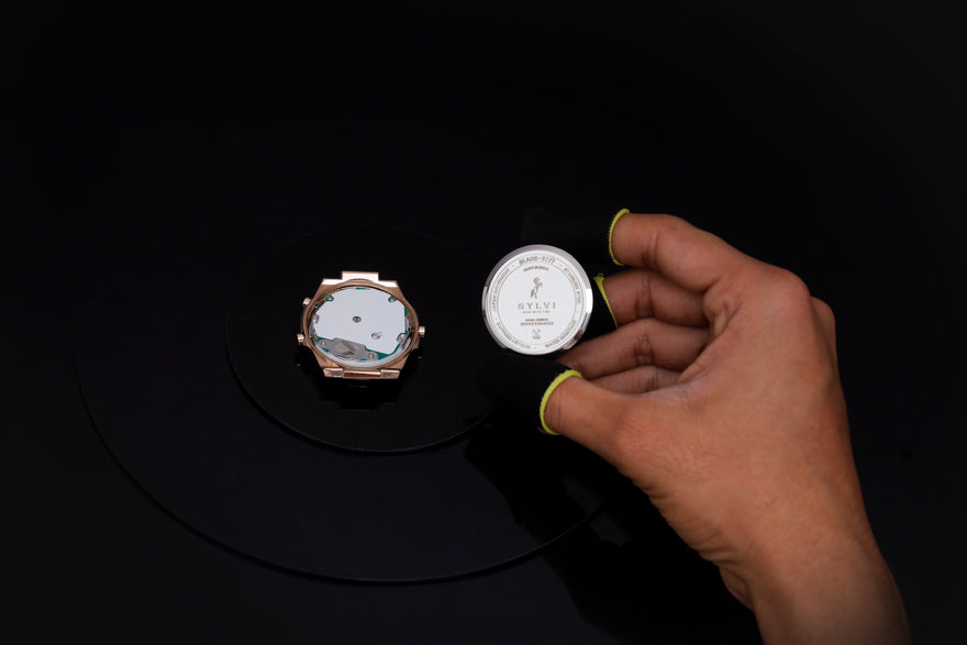 Hand holding a watch case with a dark background