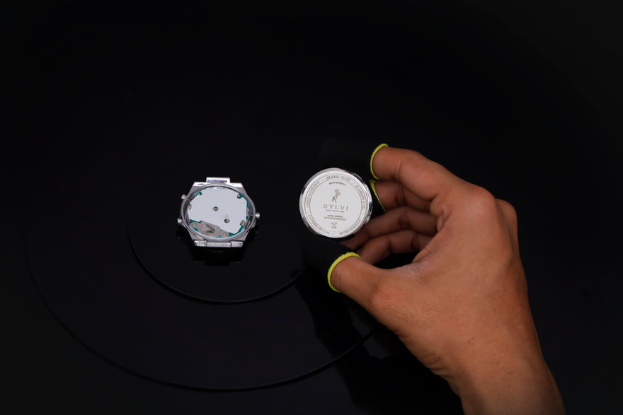 Hand holding a small round object with a label on a black background