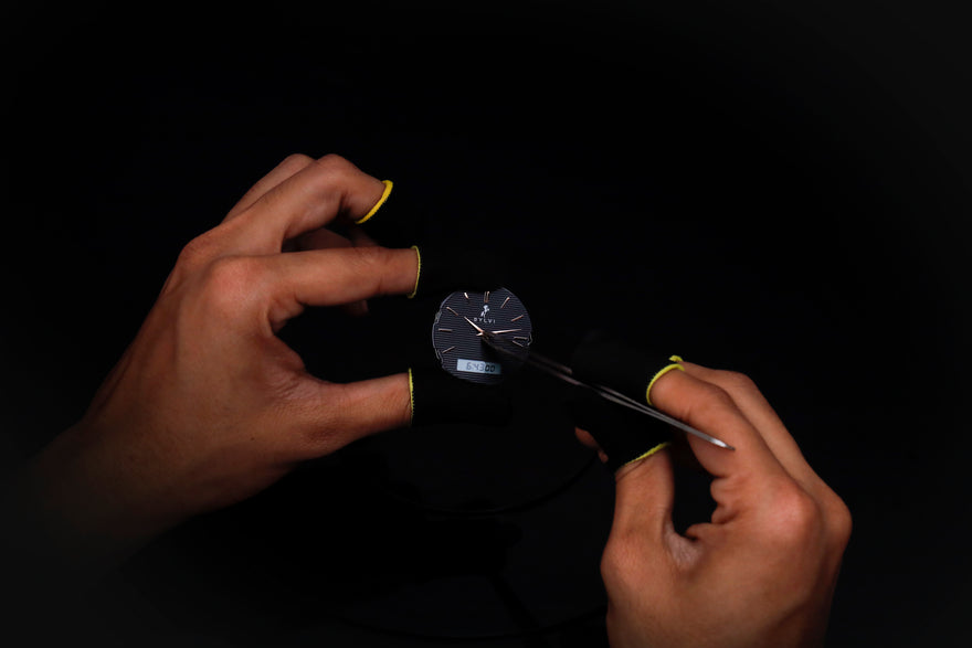 Person holding a small round object with a dark background
