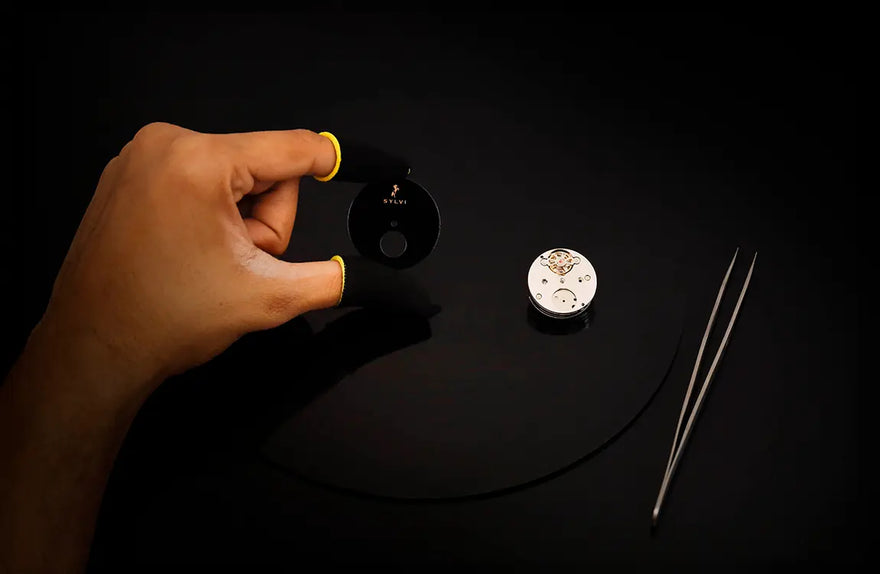Hand holding a small round object with a black background