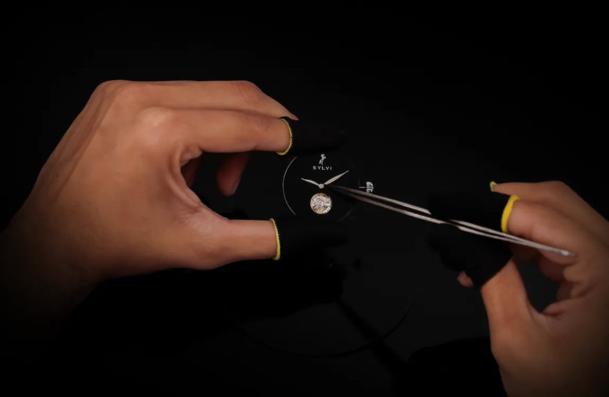 Person using tweezers to handle a small object on a dark background