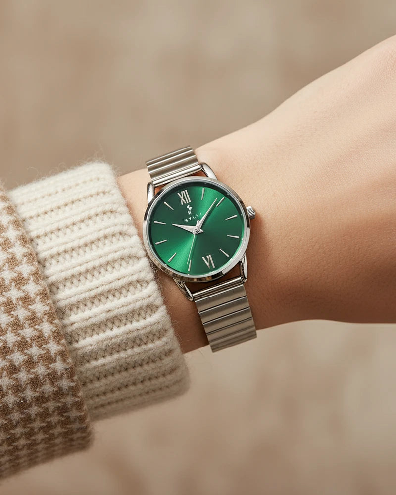 Green watch with silver strap on a wrist, blurred background