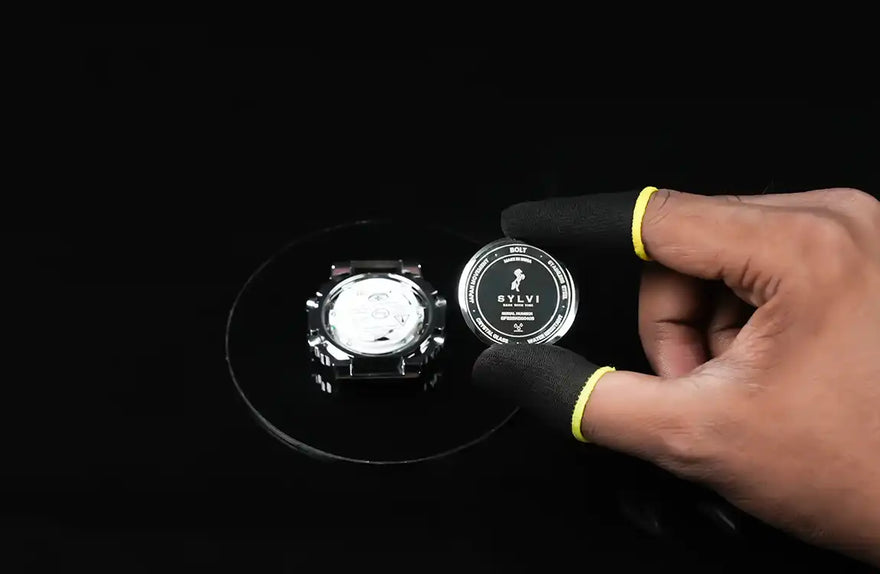 Hand holding a watch case with 'STLY' branding on a black background